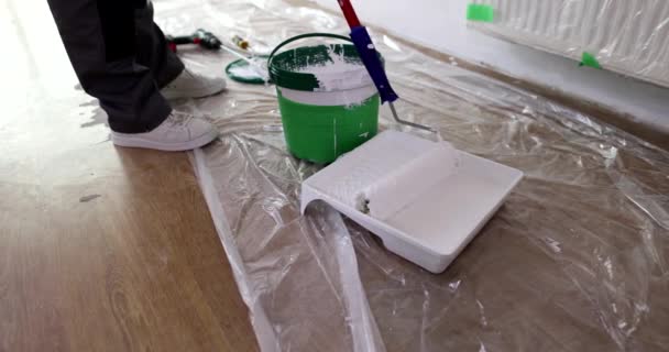 床の修理のための白い塗料の容器にローラーを閉じます 家の絵のための準備ができてトレイのローラーアプリケータ — ストック動画