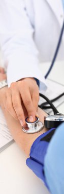 Kardiyolog doktor klinikte tonometresi olan hastaya kan basıncını ölçüyor. Atardamar hipertansiyonu tanısı ve basınçla ilgili sorunlar