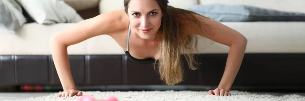 若い美しいスポーツの女の子はソファの上で自宅で演習を行う 健康的なライフスタイル 家庭でスポーツをしている女性は — ストック写真