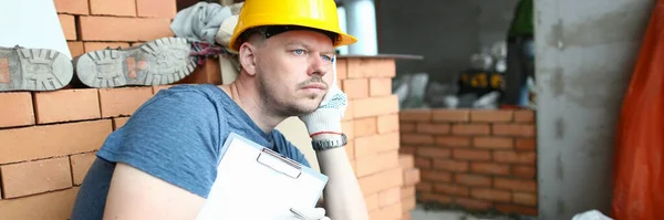 Przemyślany Smutny Budowniczy Trzymający Podkładkę Patrzący Oddali Rozwiązywanie Problemów Budowlanych — Zdjęcie stockowe