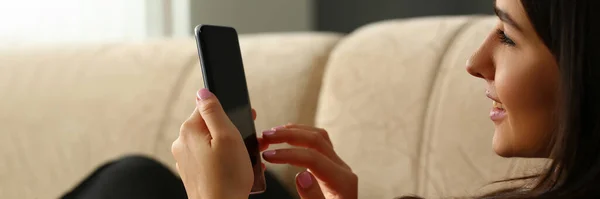 快乐愉快的女人正在舒适的沙发上休息 手里拿着智能手机 微笑的年轻女士在社交网络上聊天 看有趣的视频 — 图库照片