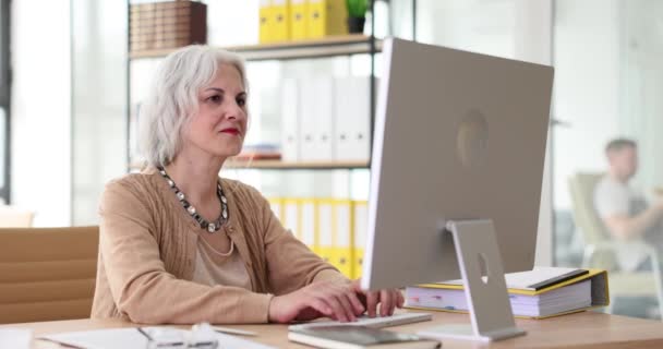 成熟的女商人坐在办公桌前 使用笔记本电脑 在办公室工作的敬业老年雇员 — 图库视频影像
