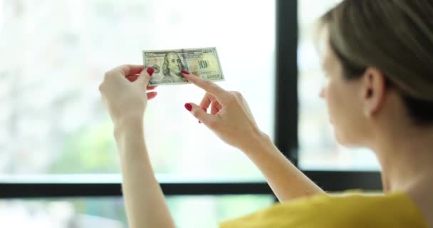 女は窓の前で金の水差しをチェックする 自宅で偽造銀行券を認識する — ストック動画