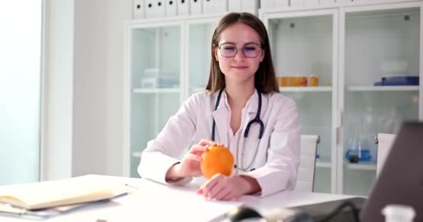 维生素C有免疫力 持橙子并推荐新鲜水果的微笑女性营养师医生的画像 — 图库视频影像