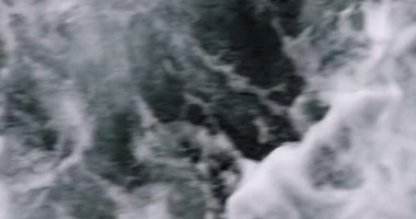 Güçlü dalgalar hızlı hareket eden tekneden kırılıyor. Beyaz köpüklü koyu mavi bir su akıntısı.