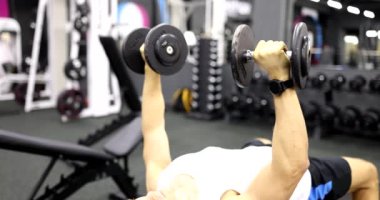 Adam yedek kulübesinde yatıyor ve spor salonunda halterli basın egzersizleri yapıyor. Vücut geliştiriciler için etkili alıştırmalar seçimi
