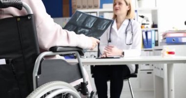 Radyolog, tekerlekli sandalyede ve omurga röntgeninde bir kadını muayene ediyor. Omurga yaralanması ve tıbbi bakım konsepti
