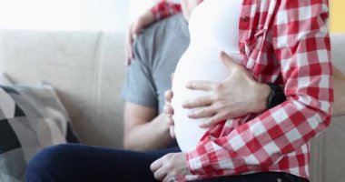 Mutlu adam hamile kadının karnını okşar. Aile kavramında çocuk doğumu beklentileri