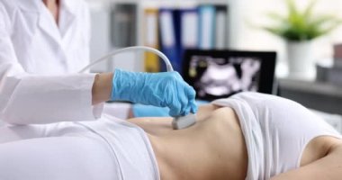 Klinikteki kadının karın boşluğunda ultrason teşhisi. Doktor ultrason sondasını hastanın karnına geçirir ve tarama panelinde çalışır. İç organların teşhisi.