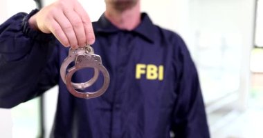 Ajan FBI üniforması elinde kelepçelerle 4K filmi tutuyor. Federal Güvenlik Hizmetleri Konsepti