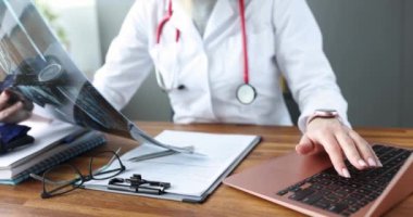 Doktor çalışma masası 4K filminde röntgeni inceliyor. Coronavirüs enfeksiyonu olan akciğerlerin görüntüsü.