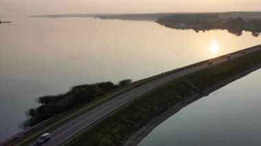 Nehrin ortasındaki köprüyle Sunset 4K filminde geçen uzun yolun robot görüntüleri. Ulaşım ve lojistik altyapı kavramı