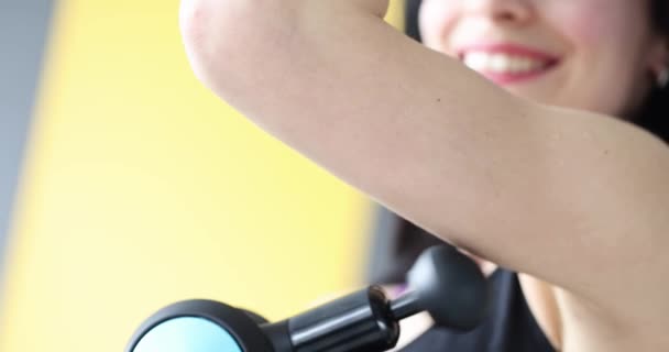パーカッションマッサージ4K動画で肩の筋肉マッサージをしている若い女性 スポーツトレーニングの概念後の筋肉の緊張を緩和 — ストック動画