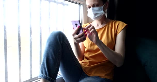 Mujer Máscara Protectora Cara Sentada Alféizar Ventana Con Teléfono Sus — Vídeo de stock