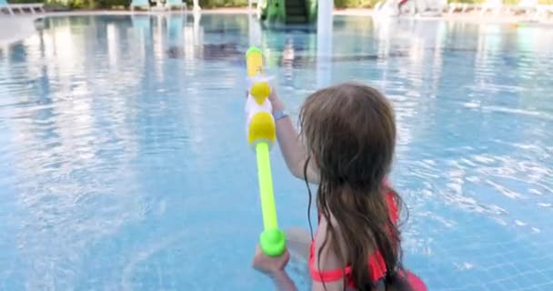 小女孩在游泳池4K电影中拍摄水枪 为儿童提供的关于水概念的娱乐和娱乐 — 图库视频影像