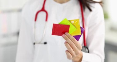 Doktor elinde 4K filminde çok renkli prezervatifler tutuyor. Cinsel yolla bulaşan enfeksiyon kavramının önlenmesi