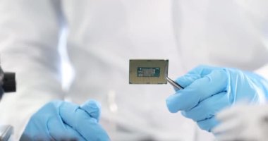 Laboratuvar 4K yavaş çekimde elinde cımbızla bilgisayar işlemcisi tutan usta bir tamirci. Bilgisayar donanımı konseptinin onarımı