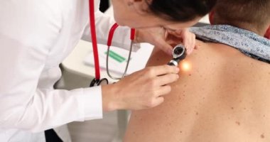 Doktor onkolog dermatoskop 4k filmi kullanarak hasta pigmentli nevusu inceliyor. Melanom konseptinin teşhisi ve tedavisi