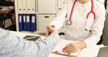 Klinikteki 4K filminde hasta doktor elini sıkıyor. Yüksek kaliteli tıbbi bakım konsepti