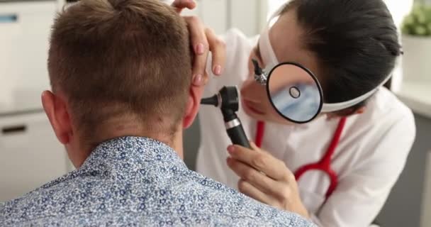 Otorhinolaryngologist Frontális Reflektorral Homlokán Vizsgálja Beteg Fülét Otoszkóppal Film Diagnózis — Stock videók
