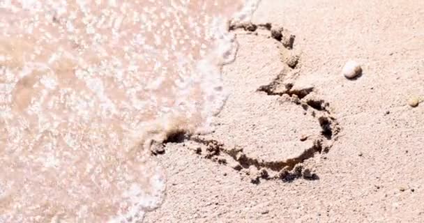 ビーチの砂の上に描かれた心の波の海4K映画から洗浄されました 世界中の観光と旅行のコンセプト — ストック動画