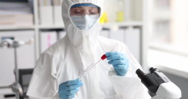 Koruyucu giysili ve solunum cihazlı doktor 4K filminde test tüpünden pamuk örneği alıyor. Koronavirüs enfeksiyonu kavramı için PCR testi