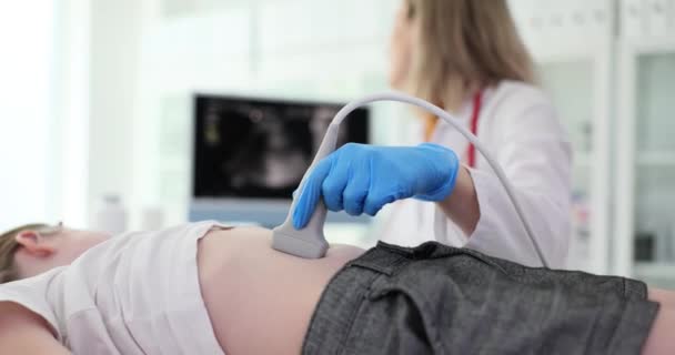医師は 診療所でスキャナを使用して女の子の腹腔の超音波を作ります 医師は患者の腹部に超音波検査を実行し 画面を見て — ストック動画