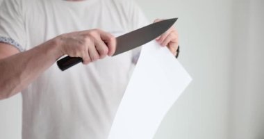 Keskin bıçakla beyaz kağıt kesiyor. Kağıt kesen adam