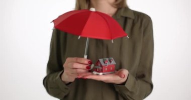 Kadın emlakçı elinde kırmızı şemsiye ve ev tutuyor. Ev ve gayrimenkul sigortası mülk sigortası kavramı
