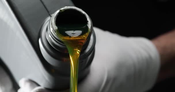 机油从一只手拿着的罐子倒在黑色的背景上 汽车用机油和润滑油 — 图库视频影像