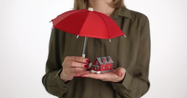 女のリアクターは赤い傘と家を持っています 不動産保険不動産保険の概念 — ストック動画