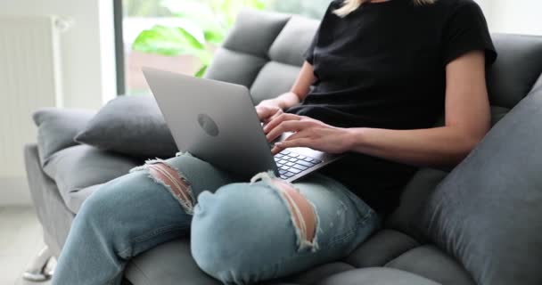 女人坐在沙发上使用笔记本电脑 在键盘上打字 还写电子邮件 人们在社交网络上输入消息或在互联网上搜索信息 — 图库视频影像