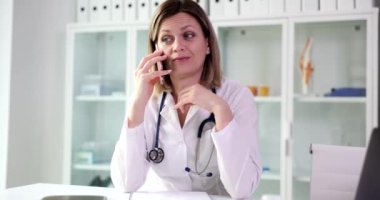 Doktor telefon danışmanlığı yapıyor ve hastayla cep telefonuyla konuşuyor. Pratisyen hekim ve danışman yardım hattındaki soruları cevaplıyor.