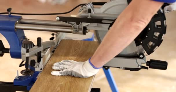 Mann Schutzhandschuhen Arbeitet Mit Gehrungssäge Und Schneidet Holzplatten Aus Laminat — Stockvideo