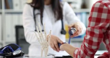 Doktor bir kadının bileğini bandajlıyor, yakın plan. Travmatoloğu ziyaret et, tendonu burkulmuş.