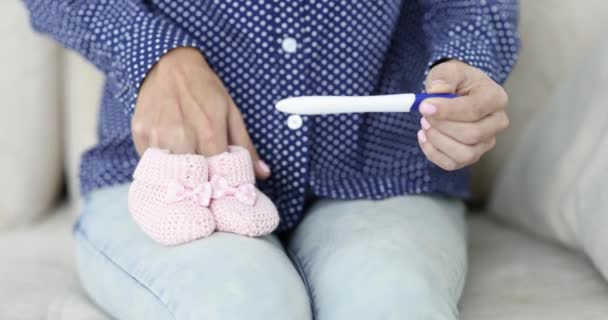 Mujer Sentada Sofá Con Prueba Embarazo Sosteniendo Botines Rosados Película — Vídeo de stock