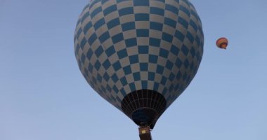 A balloon with a checkerboard pattern flies across the sky, close-up. Aeronautics festival, balloon control