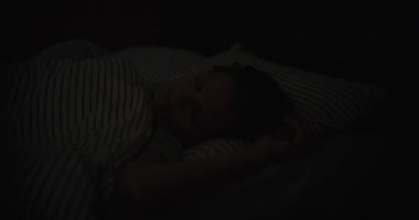 On a sleeping woman, a shadow from a lightning flash outside the window, close-up. Comfortable bedroom, good sleep