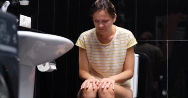 A woman is sitting on the toilet, having difficulty defecation. Bowel problem, constipation. Inflammation of hemorrhoids
