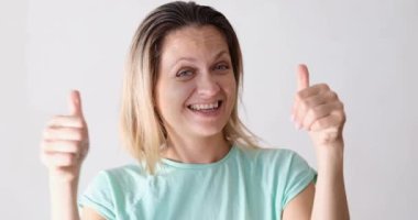 Gülen kadın başparmağını kaldırıyor, yakın plan. Neşeli duygular, olumlu duygular, yüz ifadeleri ve jestler.