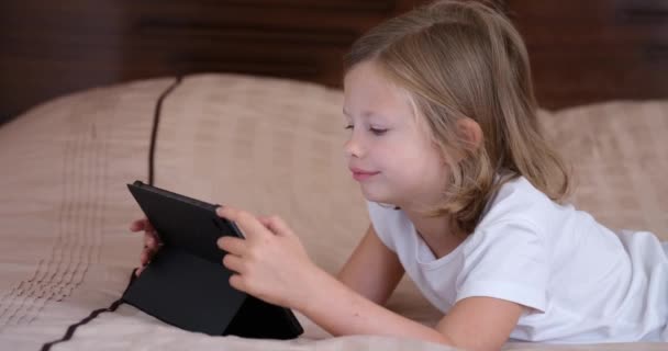 Small Girl Lying Sofa Looks Screen Tablet Close Home Schooling — Video