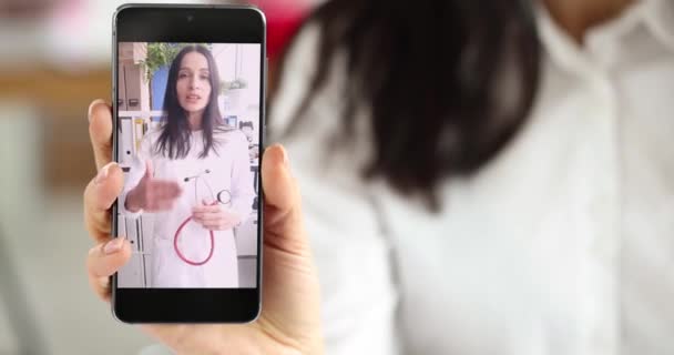医者がビデオリンク4K映画で話している彼女の手に携帯電話を持っている女性 医療ウェブセミナーのコンセプト — ストック動画