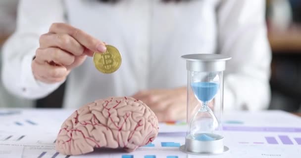 Geschäftsfrau Hält Bitcoin Münze Vor Gehirn Attrappe Und Sanduhr Film — Stockvideo