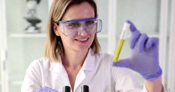 科学者は天然の製品抽出油とバイオ燃料をテストする 化学研究所で黄色の溶液を保持する科学者 — ストック動画