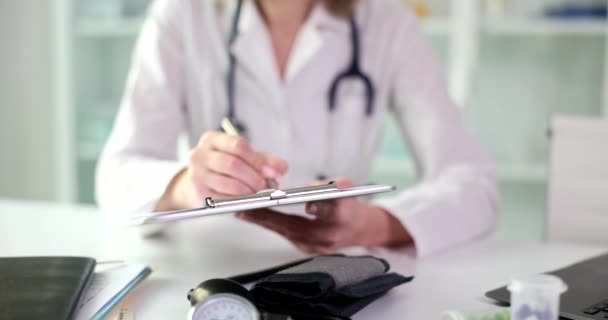 医者はテーブルに座り 患者のために処方箋を書きます 医療文書の登録 — ストック動画