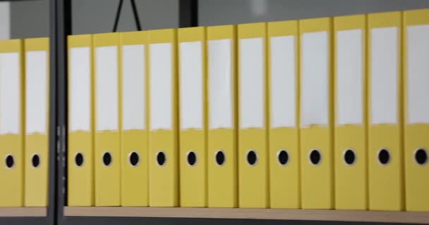 黄色のフォルダの背骨に白いラベルが付いているモックアップ行の木製の棚にオフィス文書が立っている 事業文書の保存 — ストック動画