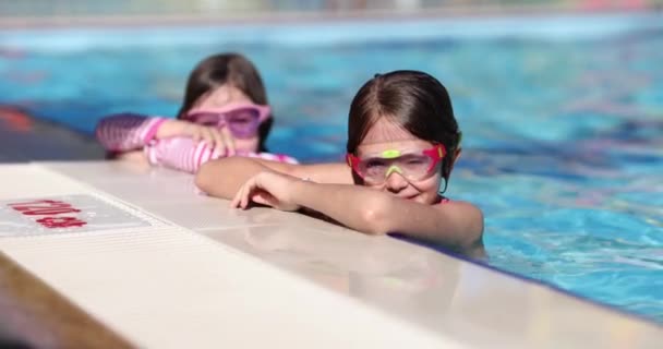 快乐的孩子们 穿着眼镜在游泳池边休息 朋友或姐姐在游泳池里享受暑假 — 图库视频影像