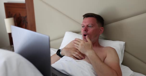 Junger Erwachsener Mann Schockiert Über Informationen Laptop Bett Liegend Freelancer — Stockvideo