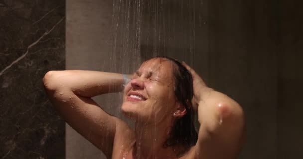 美しい女性は熱いシャワーで流れる水の下でリラックスしている間シャワーを取る シャワーでリラックスした時間を楽しむ大人の白人女性の閉鎖 — ストック動画