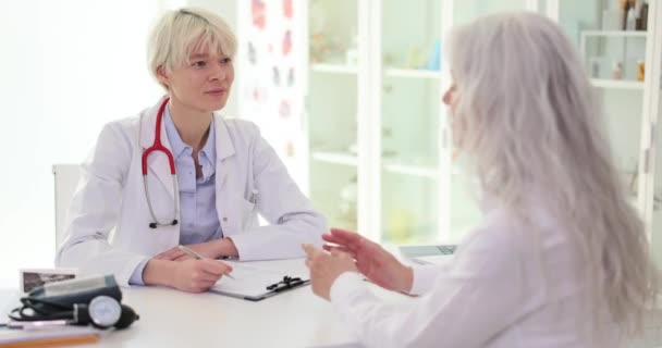 Dokter Aandachtig Luistert Naar Oudere Vrouwelijke Patiënt Met Ziekte Opschrijven — Stockvideo